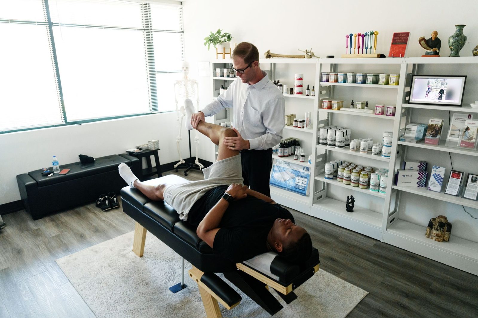 Dr. Sean Olenek assessing an athlete's hip and leg on the adjustment table