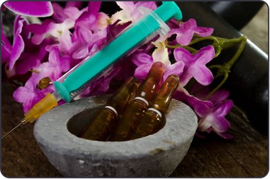 Homeopathic injectable ampoules in a stone mortar with a syringe and orchids