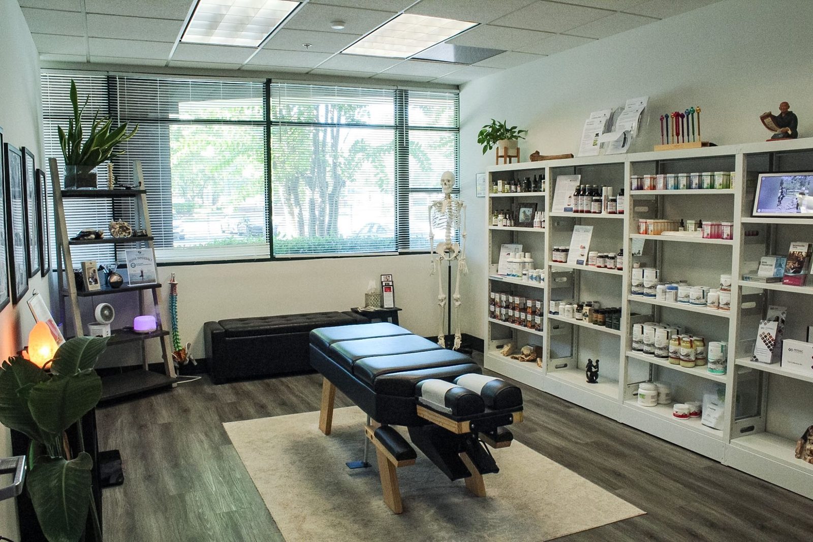 Main treatment room with adjustment table, supplement shelves and natural light